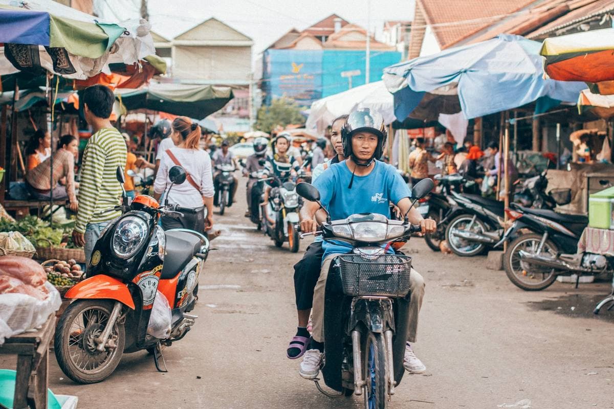 A busy market street in Cambodia, scooters among the stalls