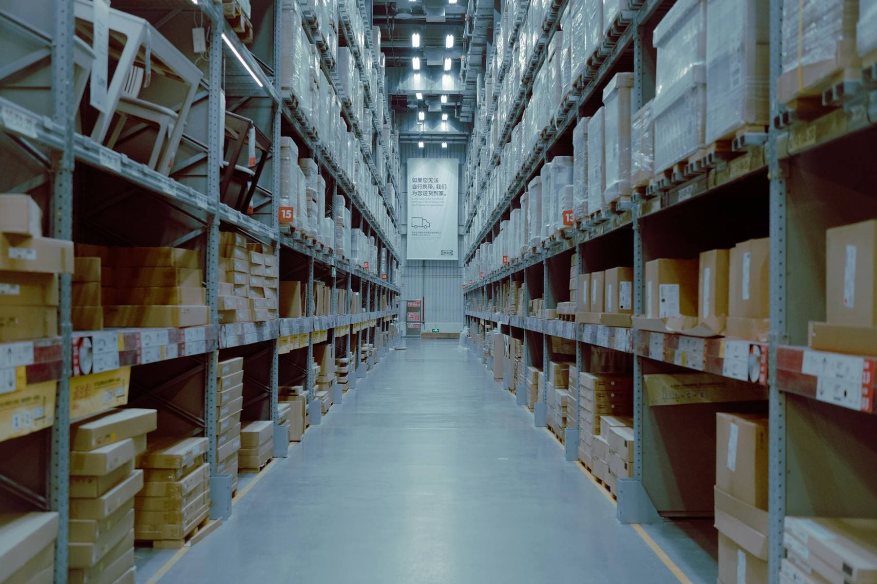A long warehouse aisle, shelves of boxed stock on both sides