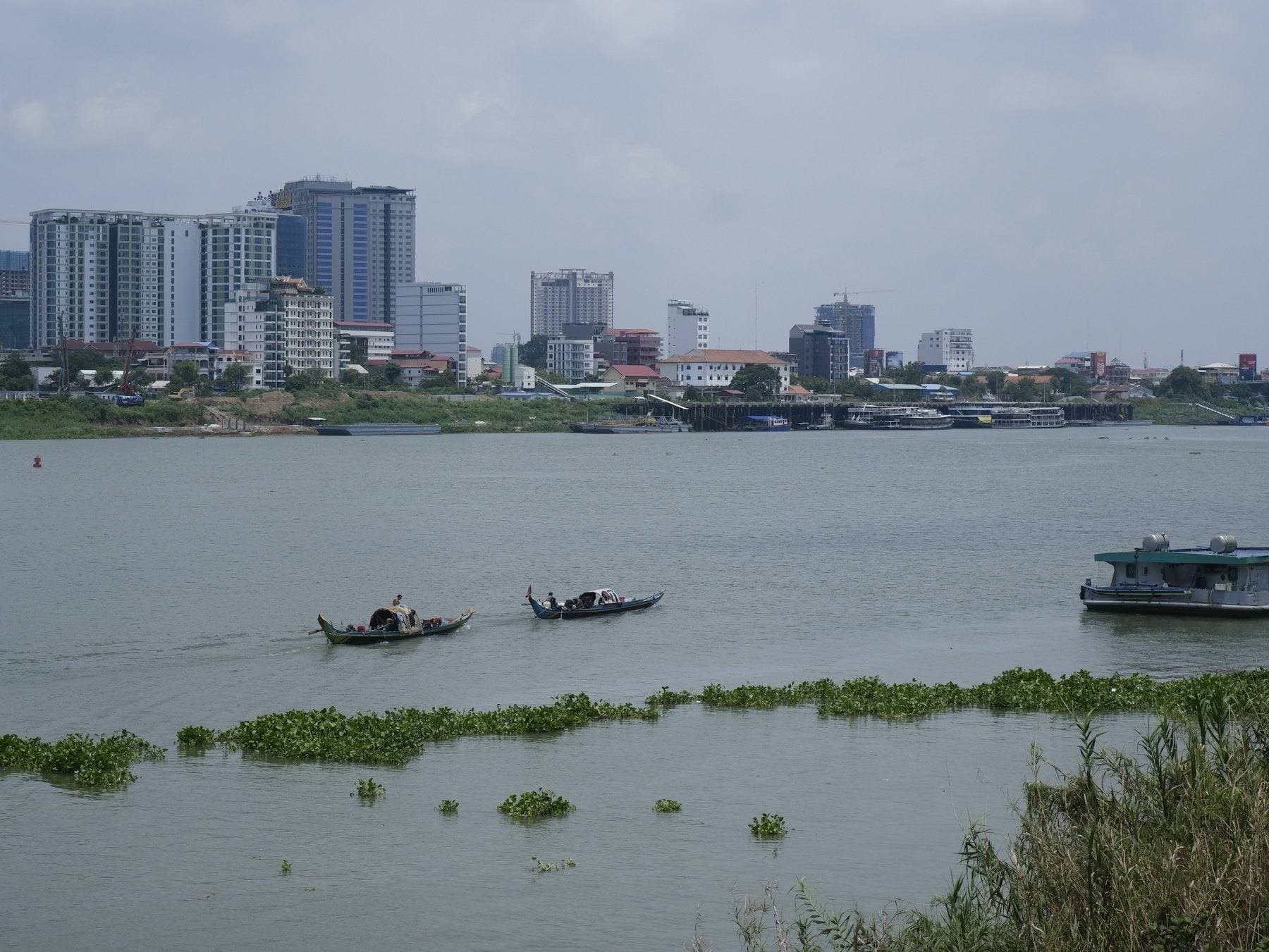 Phnom Penh's skyline across the river, two small boats on the water
